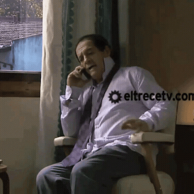 A Man Is Sitting In A Chair Talking On A Cell Phone With Eltrecetv.com Written On The Bottom GIF