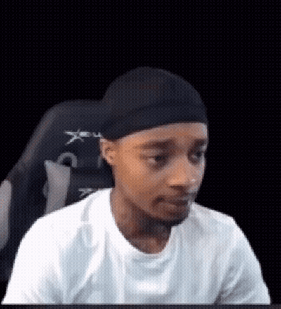 A Man Is Sitting In A Chair Wearing A Headband And A White Shirt . GIF
