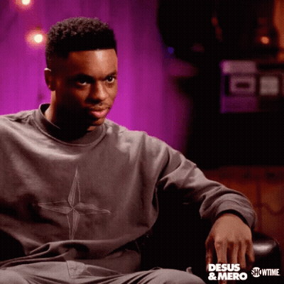 A Man Is Sitting In A Chair Wearing A Sweatshirt That Says " Desus & Mero " GIF