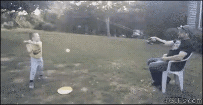 A Man Is Sitting In A Chair While A Boy Throws A Frisbee In The Air . GIF