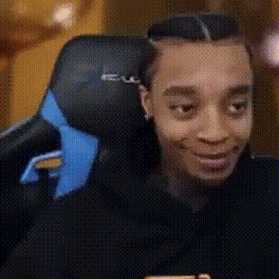 A Man Is Sitting In A Chair With A Blue Headrest And Smiling . GIF