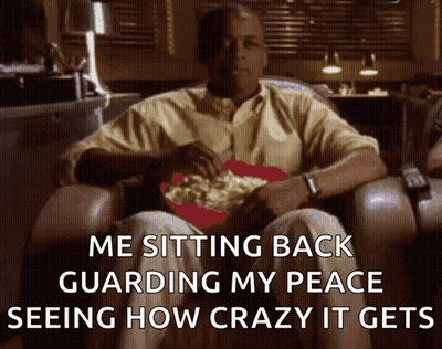 A Man Is Sitting In A Chair With A Bowl Of Popcorn On His Lap And The Caption Says Me Sitting Back Guarding My Peace GIF