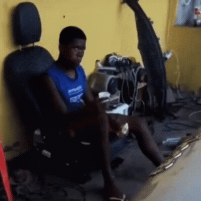 A Man Is Sitting In A Chair With A Coca Cola Bottle On The Wall Behind Him GIF