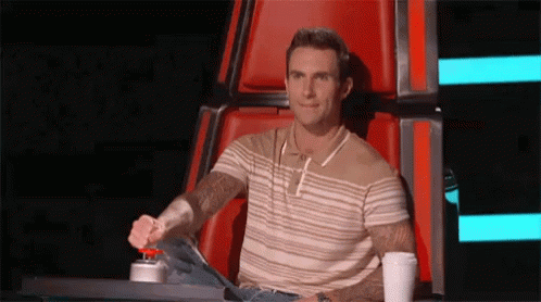 A Man Is Sitting In A Chair With A Cup Of Coffee And A Red Button . GIF