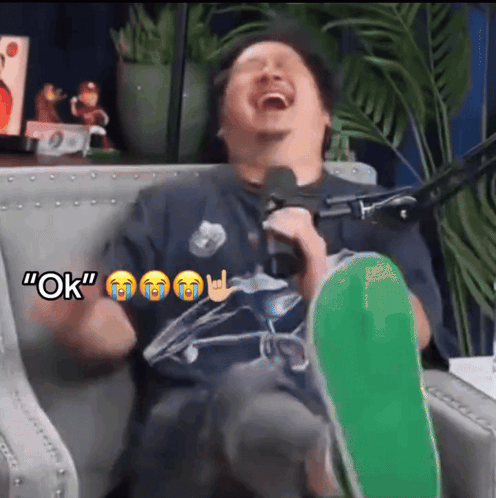 A Man Is Sitting In A Chair With A Green Skateboard And Says " Ok " In The Corner GIF
