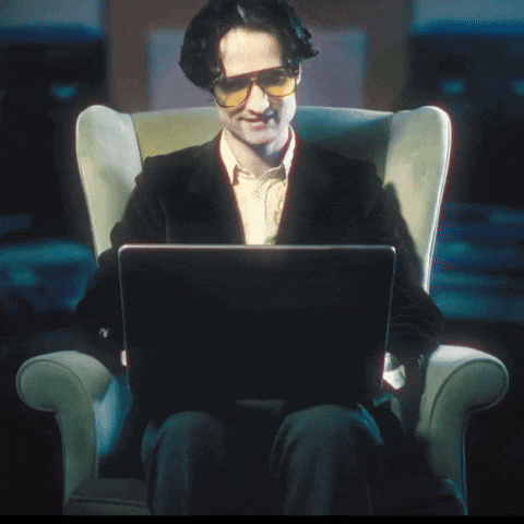 A Man Is Sitting In A Chair With A Laptop That Says Oops On It GIF