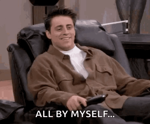 A Man Is Sitting In A Chair With A Remote Control In His Hand . GIF