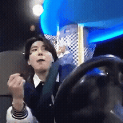 A Man Is Sitting In A Chair With A Steering Wheel In Front Of Him And Making A Funny Face . GIF