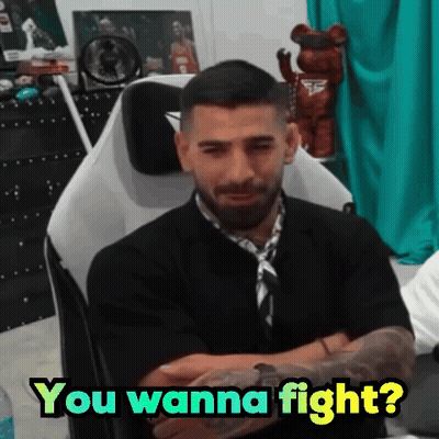 A Man Is Sitting In A Chair With His Arms Crossed And Says " You Wanna Fight ? " GIF