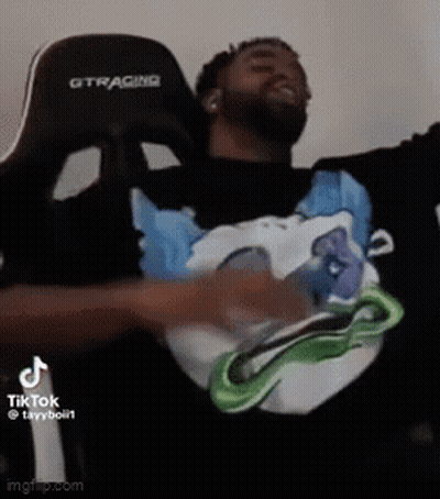 A Man Is Sitting In A Chair With His Arms Outstretched And Wearing A Black Shirt With A Picture Of A Dog On It GIF