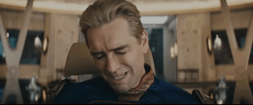 A Man Is Sitting In A Chair With His Eyes Closed And A Smile On His Face . GIF