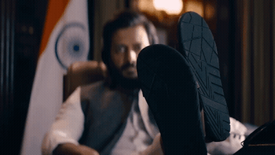 A Man Is Sitting In A Chair With His Feet Up In Front Of A Flag GIF