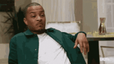 A Man Is Sitting In A Chair With His Hand On His Shoulder . GIF