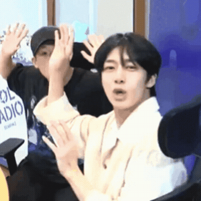 A Man Is Sitting In A Chair With His Hands Up . GIF