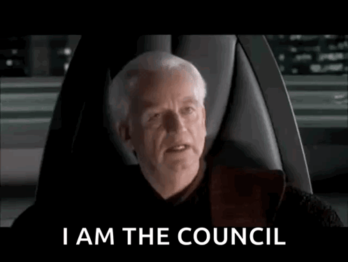 A Man Is Sitting In A Chair With The Words I Am The Council On The Screen Behind Him . GIF