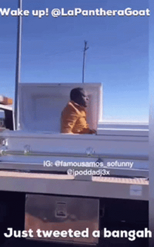 A Man Is Sitting In A Coffin On The Back Of A Truck .. GIF