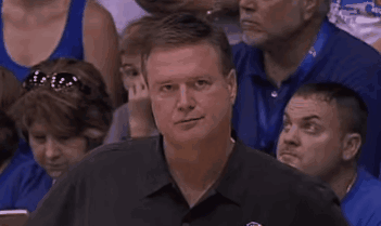 A Man Is Sitting In A Crowd Of People Watching A Basketball Game . GIF