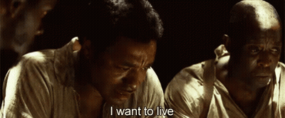 A Man Is Sitting In A Dark Room And Saying I Want To Live . GIF