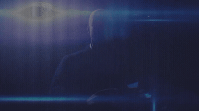 A Man Is Sitting In A Dark Room With A Blue Light Behind Him GIF