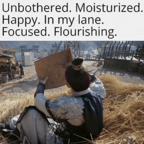 A Man Is Sitting In A Field Holding A Piece Of Paper With The Caption Unbothered Moisturized GIF