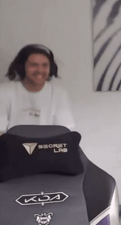 A Man Is Sitting In A Gaming Chair With A Pillow On It . GIF