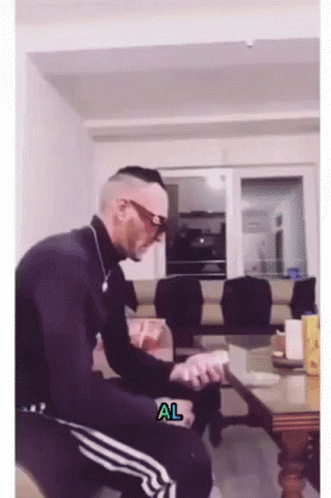 A Man Is Sitting In A Living Room With A Sticker That Says Al GIF