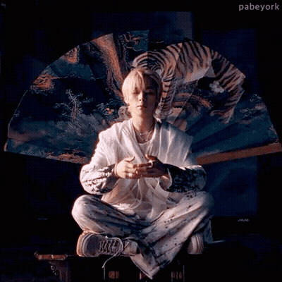 a man is sitting in a lotus position holding a fan with a picture of a tiger on it .