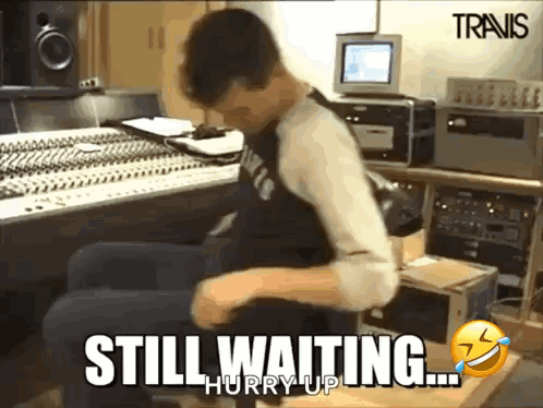 A Man Is Sitting In A Recording Studio With The Words Still Waiting Hurry Up On The Bottom GIF