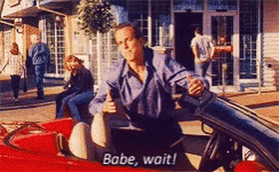 A Man Is Sitting In A Red Car And Says " Babe Wait " GIF