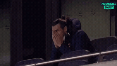 A Man Is Sitting In A Stadium Covering His Face With His Hands While Watching A Football Game . GIF