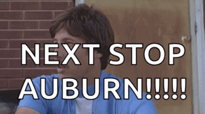 A Man Is Sitting In Front Of A Brick Wall And Says Next Stop Auburn GIF