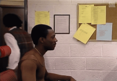 A Man Is Sitting In Front Of A Bulletin Board With A Snl Logo On It GIF