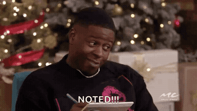 A Man Is Sitting In Front Of A Christmas Tree And Writing On A Piece Of Paper With The Words Noted Written On It . GIF
