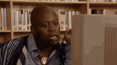 A Man Is Sitting In Front Of A Computer In A Library . GIF