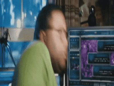 A Man Is Sitting In Front Of A Computer Screen . GIF
