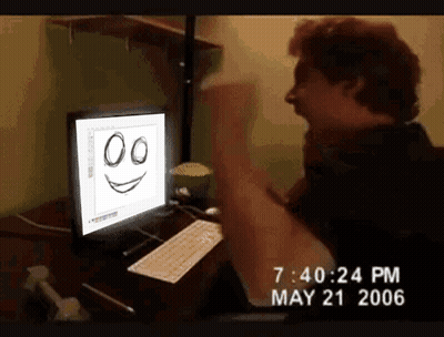 A Man Is Sitting In Front Of A Computer With A Smiley Face On It GIF