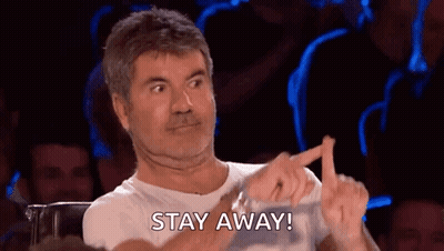 A Man Is Sitting In Front Of A Crowd Making A Funny Face And Pointing At Something . GIF