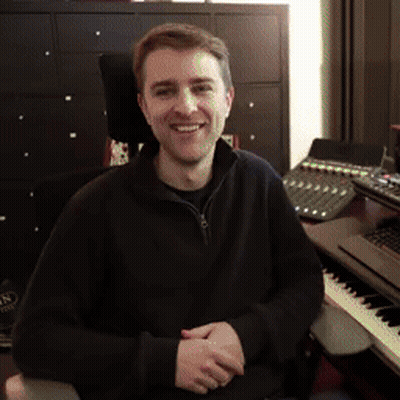 A Man Is Sitting In Front Of A Keyboard And Smiling GIF