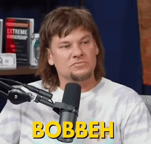 A Man Is Sitting In Front Of A Microphone And The Word Bobbeh Is On His Shirt GIF