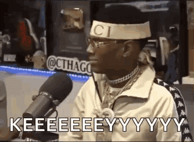 A Man Is Sitting In Front Of A Microphone Wearing A Headband With The Word Gucci On It . GIF