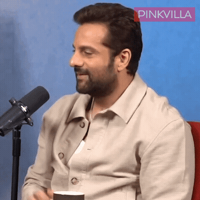 A Man Is Sitting In Front Of A Microphone With A Pinkvilla Logo In The Corner GIF
