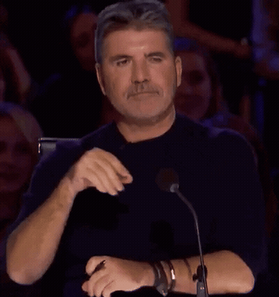 A Man Is Sitting In Front Of A Microphone With His Hands Folded And A Crowd Behind Him . GIF