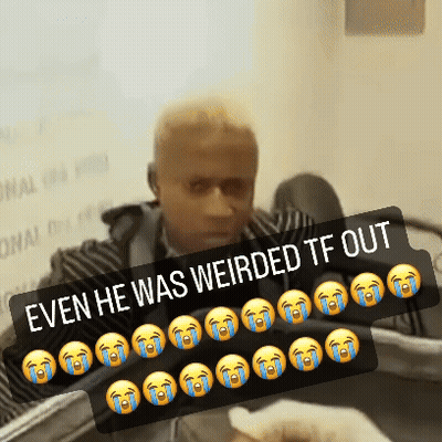 A Man Is Sitting In Front Of A Sign That Says " Even He Was Weird Tf Out " GIF