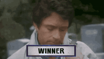 A Man Is Sitting In Front Of A Sign That Says " Winner " GIF