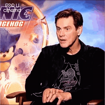 A Man Is Sitting In Front Of A Sonic The Hedgehog Poster GIF