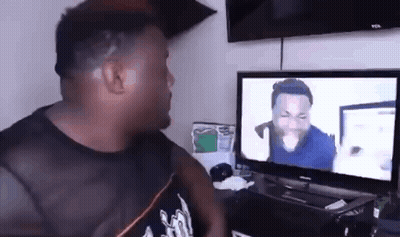 A Man Is Sitting In Front Of A Television Watching A Video . GIF