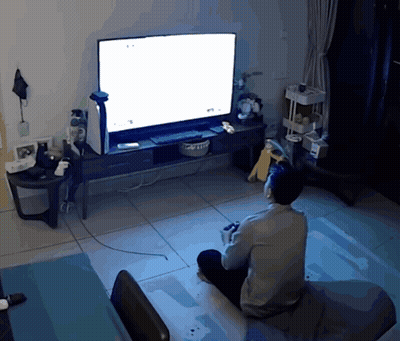 A Man Is Sitting In Front Of A Television With A White Screen GIF