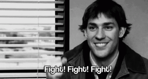A Man Is Sitting In Front Of A Window With Blinds And Smiling . GIF