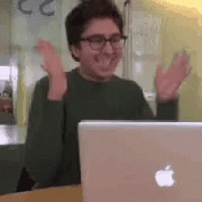 A Man Is Sitting In Front Of An Apple Laptop Computer . GIF