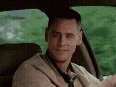 A Man Is Sitting In The Back Seat Of A Car Looking At The Camera . GIF